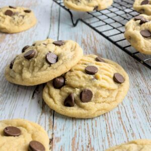 Soft chocolate Chip Cookies on a table and cooling rack.