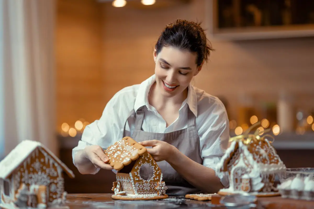A woman assembling a gingerbread house.