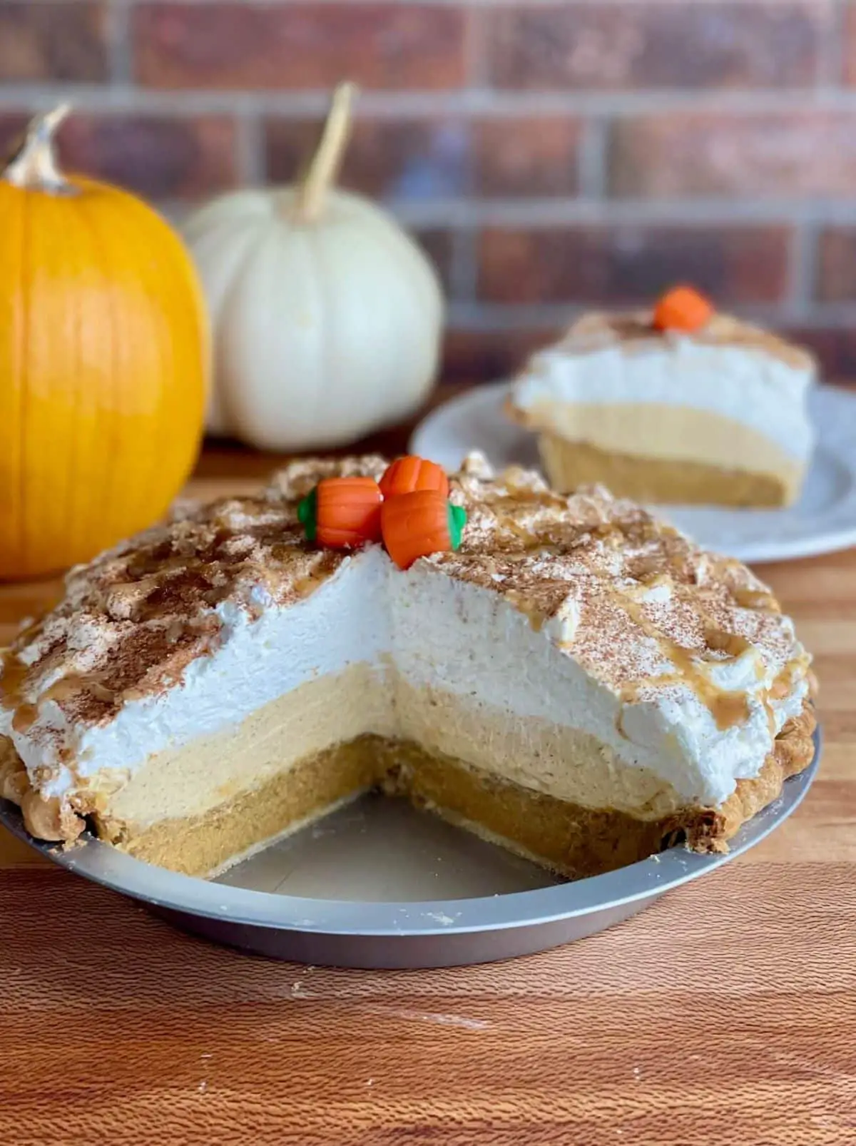 A whole Pumpkin Cream Pie cut open to show layers of pumpkin pie, pumpkin mousse, and whipped cream.