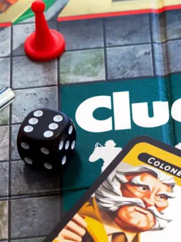 A closeup of the board game clue with a Colonel Mustard character card and a murder weapon prop.