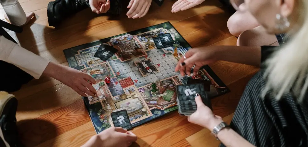 Several sets of hands playing the board game Clue.