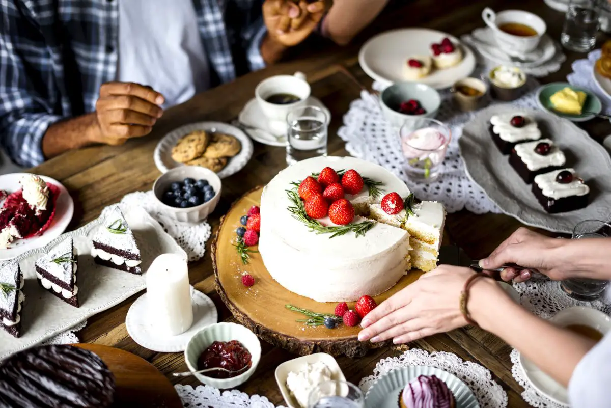 A beautiful tea cake being cut at a high tea party for adults.