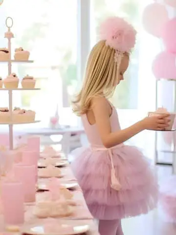 A ballerina at a pink ballet party with balloons and party decorations.