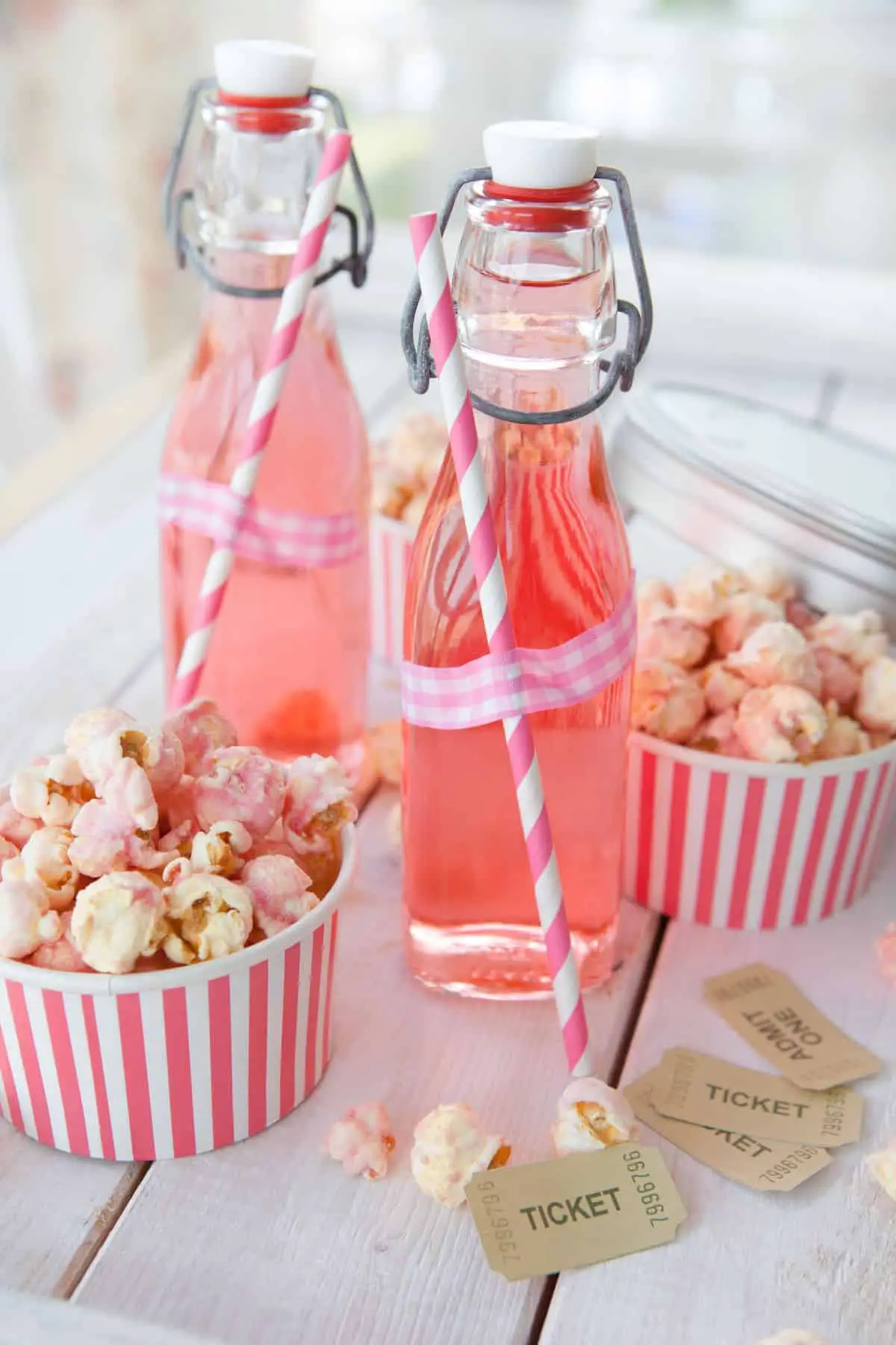 Bottles of pink lemonade and movie-themed straws and cups holding popcorn.