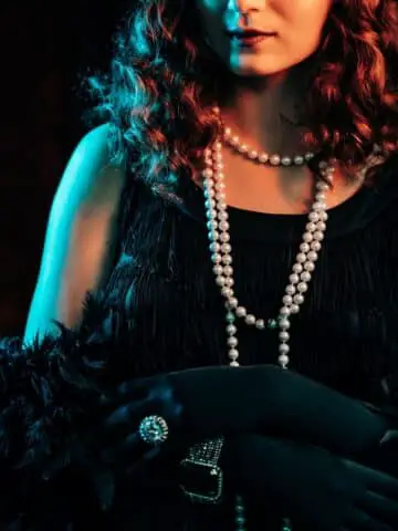 A woman in a 1920s costume with a feather boa and pearls.